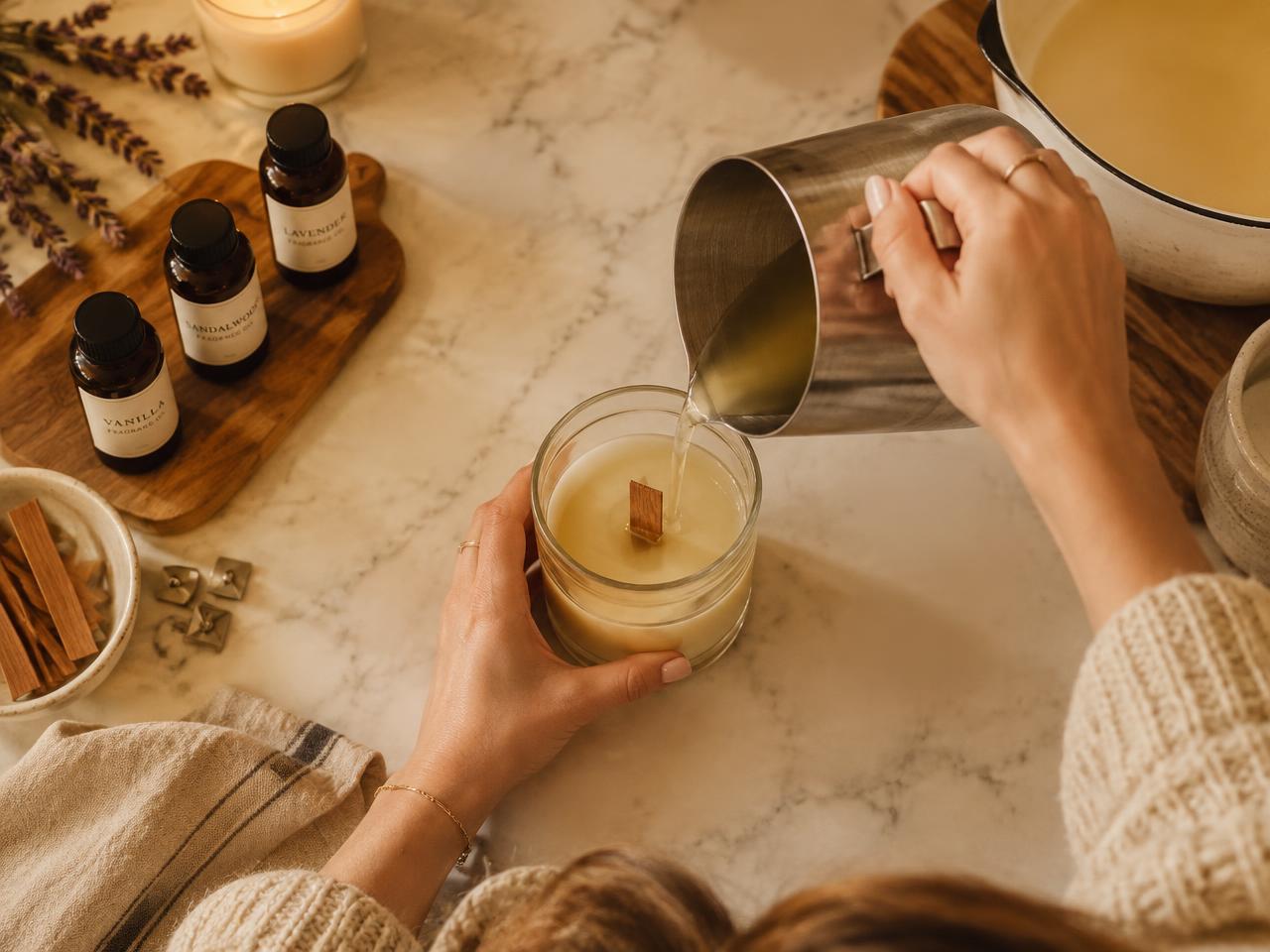 Pouring melted coconut wax into a glass jar